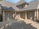 Three-car garage with carriage doors, columns, and a front entrance at 149 Cedar Woods Trl, Canton, GA 30114