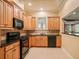 Open kitchen design with wooden cabinetry, black appliances, and granite countertops at 149 Cedar Woods Trl, Canton, GA 30114