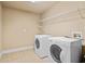 Bright laundry room with tile floors, overhead shelving, and modern washer and dryer at 149 Cedar Woods Trl, Canton, GA 30114