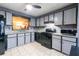 Kitchen with granite counters, tile flooring, black appliances and grey cabinets at 1023 Thornwoode Ln, Stone Mountain, GA 30083