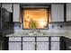 Close-up on kitchen sink, features granite counters, grey cabinets and adjacent view to living room at 1023 Thornwoode Ln, Stone Mountain, GA 30083