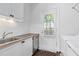 A bright laundry room with white cabinetry, stainless steel appliances and a window-covered door to the exterior at 2522 Habersham Nw Rd, Atlanta, GA 30305