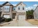 Two-story townhome with stone and shingle exterior, two-car garage, and landscaped yard at 1000 Belfry Ter, Fairburn, GA 30213