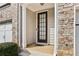 Townhome's front entrance with a brown door and stone accents at 1000 Belfry Ter, Fairburn, GA 30213