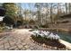 Landscaped pool area featuring a brick patio and lush greenery at 6229 Grand Loop Rd, Sugar Hill, GA 30518