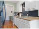 White kitchen cabinets, dark tile backsplash, and wood floors at 400 Fleeta Dr, Covington, GA 30016