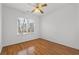 This bedroom has hardwood floors, a ceiling fan, and natural light from a large window at 8240 Knollbrook Ln, Mcdonough, GA 30253