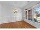 Inviting dining room featuring hardwood floors, decorative wainscoting, a chandelier, and large windows overlooking the front yard at 8240 Knollbrook Ln, Mcdonough, GA 30253