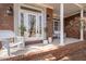 Cozy front porch featuring white seating, decorative planters, and a brick facade, perfect for relaxing outdoors at 8240 Knollbrook Ln, Mcdonough, GA 30253