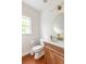 Modern bathroom with a wood vanity, an oval mirror, and terra cotta floor tiles at 673 Windsor Sw St, Atlanta, GA 30310