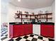 Finished basement area featuring a wet bar with red accents, black countertops, and checkered floor at 4086 Haverhill Dr, Atlanta, GA 30342