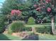 Landscaped backyard with blooming crape myrtles, manicured hedges, and tiered lawn at 1215 Wynridge Xing, Alpharetta, GA 30005