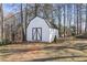 White shed with double doors in wooded backyard at 4392 Overlook Dr, Acworth, GA 30101