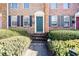 Brick townhome entry featuring a green door, black shutters, and neatly trimmed greenery at 245 Winding River Dr # E, Atlanta, GA 30350