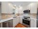 Modern white kitchen with stainless steel appliances, bright lighting, and tile backsplash at 245 Winding River Dr # E, Atlanta, GA 30350