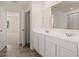 Double vanity bathroom with white cabinets and grey tile floor at 1029 Blue Juniper Cir, Loganville, GA 30052