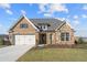 Brick house with stone accents, a three-car garage, and a landscaped yard at 2615 Yellowstone Farm Dr, Cumming, GA 30028