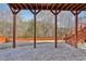 Covered patio with stone floor and wooden stairs leading to a backyard with trees at 1565 Horseshoe Creek Ln, Cumming, GA 30041