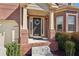 Inviting front porch featuring brick columns, a dark wooden door with wreath, and manicured shrubs at 1565 Horseshoe Creek Ln, Cumming, GA 30041