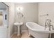 A claw foot bathtub and pedestal sink in a bathroom with tile flooring and neutral colored walls at 3611 Howell Wood Trl, Duluth, GA 30096