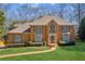 Traditional brick home with manicured lawn and garden beds leading to a front door with decorative glass and sidelights at 3611 Howell Wood Trl, Duluth, GA 30096