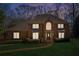 Exterior of brick home with dark shutters and inviting front entrance illuminated at dusk and green lawn at 3611 Howell Wood Trl, Duluth, GA 30096