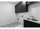 Laundry room with dark cabinetry, stainless steel sink, and tile floor at 3921 Enclave Way, Tucker, GA 30084