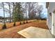 Fenced backyard featuring a concrete patio, new grass, and a lush green tree line for ultimate privacy at 96 Rome St, Temple, GA 30179