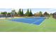 Blue tennis court with green perimeter and surrounding fencing at 5220 Otter Creek Run, Cumming, GA 30040