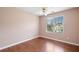 Well-lit bedroom featuring hardwood floors, ceiling fan, and large window with backyard view at 1379 Paddocks Way, Powder Springs, GA 30127