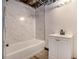 Small bath features tub and shower with marbled tile and modern fixtures at 1490 Broad Ne St, Conyers, GA 30012