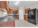 Well-lit kitchen with wood cabinets, black appliances, stone counters, and light gray wood-look flooring at 1538 Park Grove Dr, Lawrenceville, GA 30046