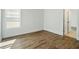 A vacant bedroom with light wood floors, white walls, a window with blinds, and a view to another room at 11335 Bennett Ln, Johns Creek, GA 30097