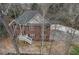 Aerial view of a brick home with green shutters, a front porch, mature trees, and a driveway at 1012 Crown River Pkwy, Mcdonough, GA 30252