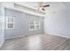 A bright primary bedroom with modern ceiling fan, tray ceiling, large windows, and gray wood flooring at 202 Bryon Ln, Acworth, GA 30102