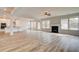 Open-concept living room with fireplace, hardwood floors, abundant natural light, and a glimpse of the kitchen at 203 Arabella Pkwy, Locust Grove, GA 30248