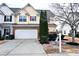 Two-story townhome with yellow siding, brick accents, and a white garage door at 2374 Suwanee Pointe Dr, Lawrenceville, GA 30043