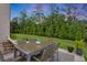 Inviting outdoor patio with dining furniture and a lush, green backyard surrounded by tall trees at 2760 Rustic Lake Ter, Cumming, GA 30041