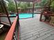 Outdoor pool with deck, seating, and red wood railings surrounded by nature at 6625 Starling Sw Pl, Mableton, GA 30126