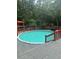 Above-ground pool with a wooden deck surround and a red perimeter fence in a wooded back yard at 6625 Starling Sw Pl, Mableton, GA 30126