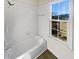 Bright bathroom with white tile, bathtub, and large window at 3905 Colonial Sw Trl, Lilburn, GA 30047
