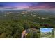 Scenic aerial view of the estate nestled within a lush, green forest with city lights in the background at 101 Barker Rd, Cumming, GA 30040