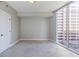 Minimalist bedroom with a large window, neutral walls and carpet, and a white door at 20 10Th Nw St # 901, Atlanta, GA 30309