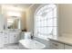 Elegant bathroom with soaking tub, marble flooring, and stained-glass window at 255 Grogans Lake Pt, Atlanta, GA 30350