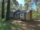 Back exterior featuring a small patio and well-maintained lawn surrounded by trees at 65 Bridge Dr, Douglasville, GA 30134