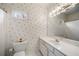 This bathroom has white walls with patterned wallpaper, a window and matching sink and toilet at 2290 Spencers Way, Stone Mountain, GA 30087
