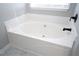 Close-up of a soaking tub with black fixtures and a marble tile surround in the bathroom at 7015 Setters Way, Lithonia, GA 30038