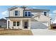 Two-story house with light brick and gray siding, a white two-car garage, and a front porch at 1569 High Falls Ln, Grayson, GA 30017
