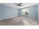 A bright bedroom with large windows, neutral carpet, a ceiling fan, and light blue walls at 2056 Wildflower Way, Conyers, GA 30012