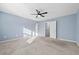 A bright bedroom with large windows, neutral carpet, a ceiling fan, and light blue walls at 2056 Wildflower Way, Conyers, GA 30012